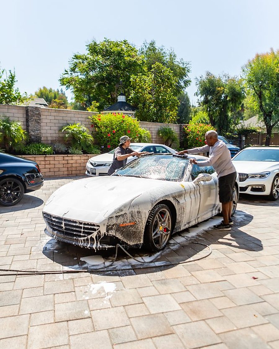 George washing a white convertible in a customer's driveway